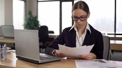 Fototapeta premium Concentrated businesswoman reading financial reports, analyzing company revenues