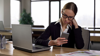 Woman checking social media on phone, distracted from work, productivity concept