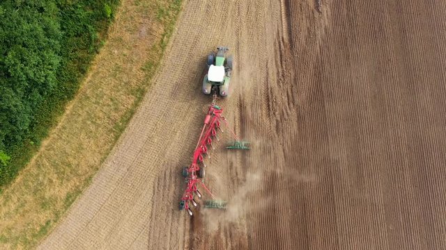 Aerial view of a agricultural tractor with a red plow during field work on one agricultural field in germany