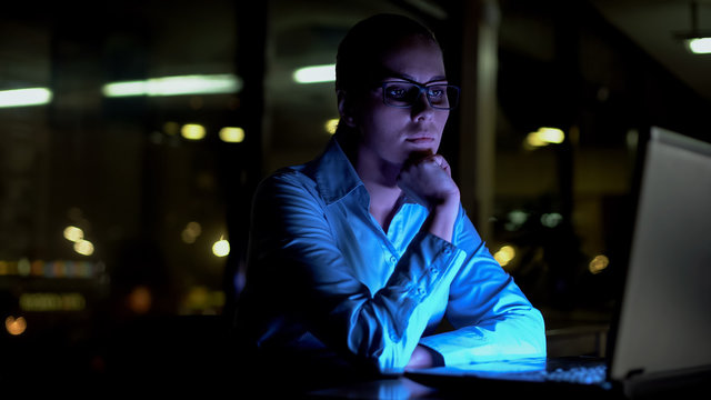 Female working extra hours at night, thinking over difficult business project