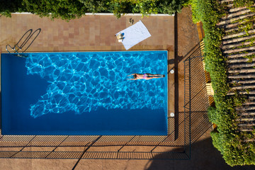 Imágenes desde dron de mujer en piscina, saltando al agua