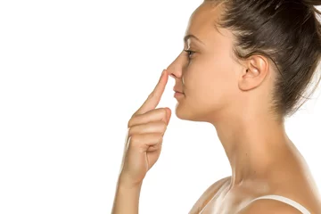 Fotobehang young woman touches her nose with her finger on a white background © vladimirfloyd