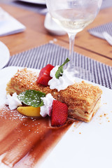 Ukrashenny puff cake with fruit and whipped cream . Very appetizing dessert.