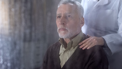 Doctor supporting sick old man, holding patient shoulder, hard time, loneliness