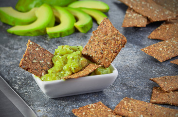 Guacamole in a bowl on a background of sliced avocado.