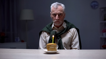Lonely old man celebrating birthday alone, forgotten by children and relatives