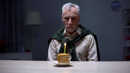 Sad granddad celebrating birthday alone with piece of cake, forgotten by family