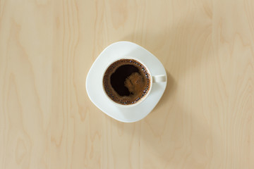 Coffee cup and saucer on a wooden table. Cup of espresso in white cup and white saucer top view. Copy space.