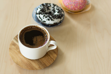 Coffee and donut for breakfast. Cup of dark espresso with sweet donut dessert.
