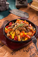 Beef fajitas with colorful vegetables in pan on old map background