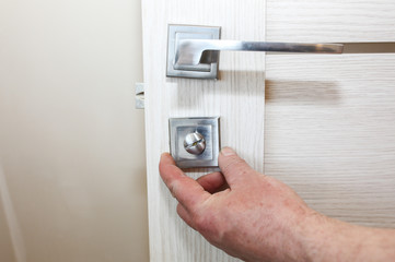 Man is installing the doors locker. Repair works. Maintenance in the apartment.