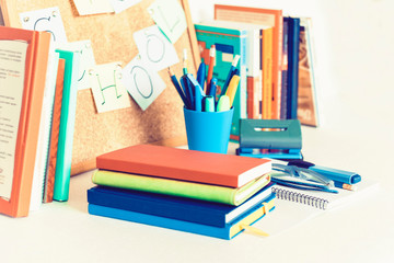 Back to school background. Stationery accessories – notebooks piles, plastic holder pencils, pens, markers, stickers, notepads, glasses and corkboard with stack of books education concept .
