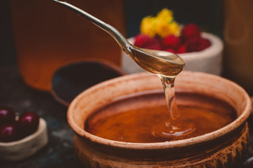 honey pour from a spoon into a clay plate