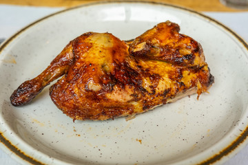 Delicious grilled chicken leg on plate in restaurant