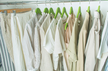summer wardrobe with linnen clothes on green hangers
