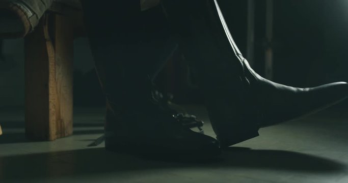 Cinematic slow motion close up of young female horsemanship master is putting on professional boots before to start a practising exercises for competition of horse racing and dressage on a riding hall