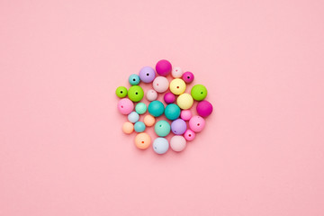 Colorful pastel beads in a circle on pink background. Girly minimalist composition