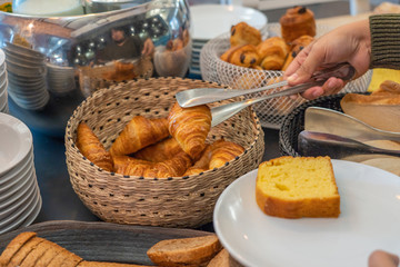 Woman having breakfast at hotel with croissant and bread