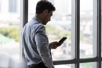 Businessman standing and using smartphone..