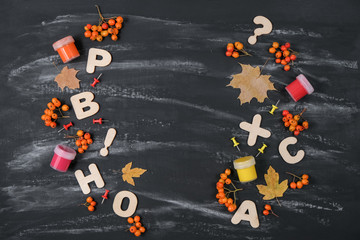 Back to school concept. Colored pencils, rowan, gouache and dried maple leaves and office supplies on black table background. Flat lay, top view, copy space.