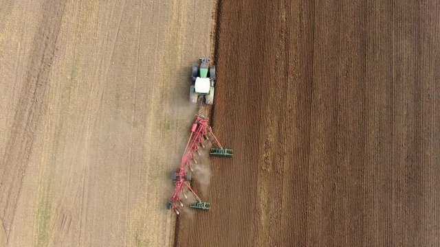 Aerial view of a agricultural tractor with a red plow during field work on one agricultural field in germany
