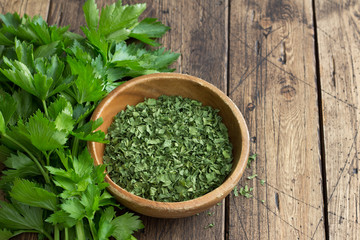 Dried green celery in a wooden bowl and fresh celery on a wooden table	