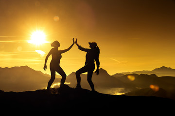 Zwei Frauen beim Abklatschen auf einem Berggipfel