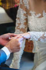 Groom wearing ring to bride in wedding ceremony..