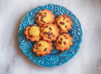 Delicious French madeleine cakes with raisins served  on a blue plate, top view