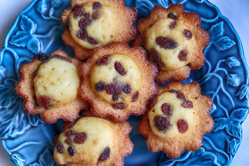 Delicious French madeleine cakes with raisins served  on a blue plate, close up top view