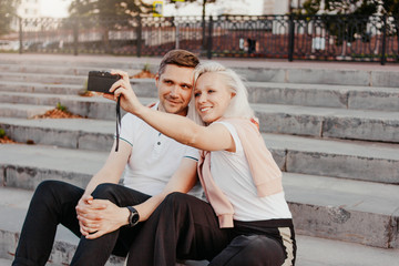 Fototapeta premium Young happy couple in love making selfie on retro camera on city street