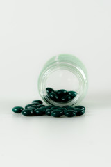 isolated close up of green pills and glass prescription bottle