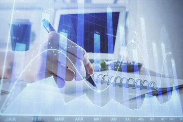 Financial forex graph drawn over hands taking notes background. Concept of research. Multi exposure