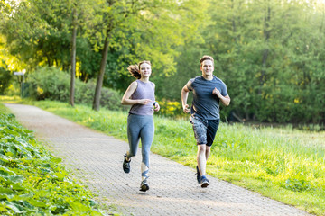 Naklejka premium young woman and man running in a forest and making fitness