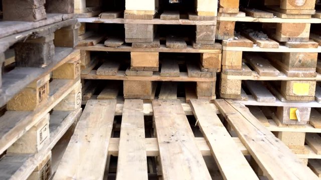 Wooden euro pallets for transfering goods to customers. Used wooden pallets in stack in the warehouse. Wooden pallet overlap.