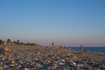 wild pebble beach on the sea with people
