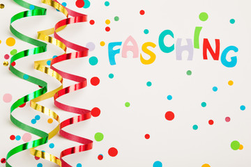 Confetti, paper streamers and colorful letters saying carnival (in German)