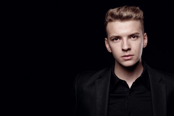 Fototapeta premium young man in black jacket on black background