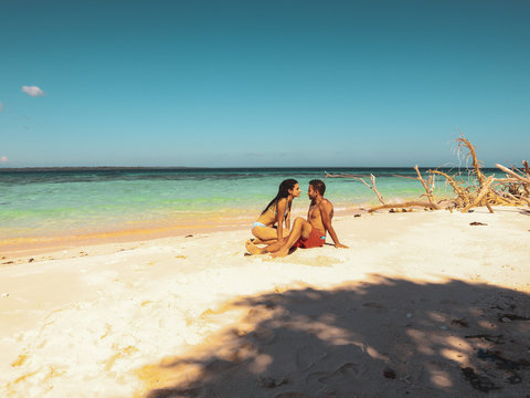 Lovely couple relaxing at the white sandy beach with palm trees in Onok Island in Balabac Palawan in Philippines