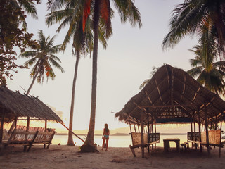 Woman watching sunset with palm trees in Candaraman Island in Balabac Philippines