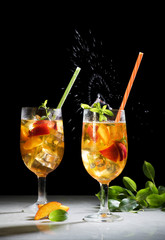 Peach ice summer cocktail or tea, sangria with peach with beautiful splash, copy space, black background