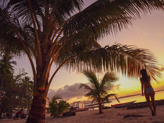 Woman watching sunset with palm trees in Candaraman Island in Balabac Philippines