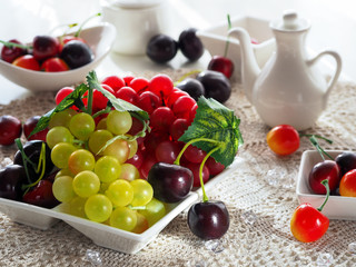 Fruits for breakfast. Healthy food. Нealthy lifestyle. Vegan food. Vegan diet. Red and green bunches of grapes, cherry lie on a white dish
