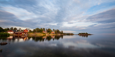 Schwedische Landschaft mit roten Häusern am Meer. Swedish landscape at seaside with red houses.