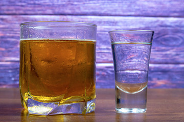 Vodka and beer in different glasses on a wooden table