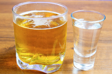 Vodka and beer in different glasses on a wooden table
