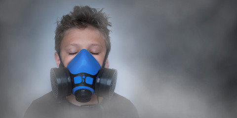 Young boy wearing gasmask, respirator portrait. Effects of worldwide air pollution, industrial...