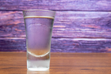 Cold glass of vodka on a wooden table