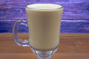 Latte coffee in a tall glass on a wooden table