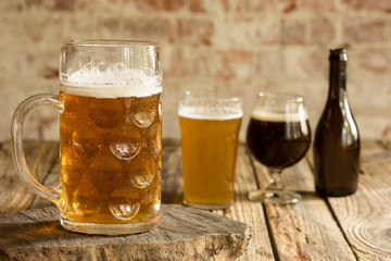 Glasses of different kinds of dark and light beer on wooden table in line. Cold delicious drinks are prepared for a big friend's party. Concept of drinks, fun, meeting, oktoberfest.
